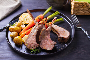 Roasted rack of lamb. Lamb chops with vegetables on black plate