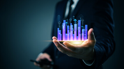 Businessman holding glowing bar chart with upward arrows, symbolizing business growth, financial...