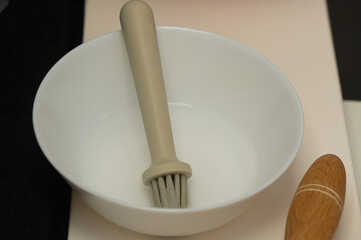 Simple kitchen setup featuring a white bowl with a brush and a wooden rolling pin for culinary preparations