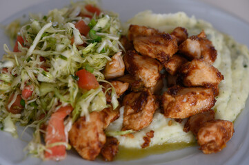 Delicious grilled chicken served on creamy mashed potatoes with fresh salad on a sunny afternoon