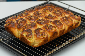 Freshly baked loaf of golden, pillowy rolls adorned with vibrant spices cooling on a rack in a cozy kitchen setting during the afternoon