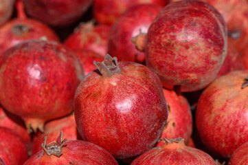 Vibrant pomegranates stacked together at a bustling market during a sunny afternoon in autumn