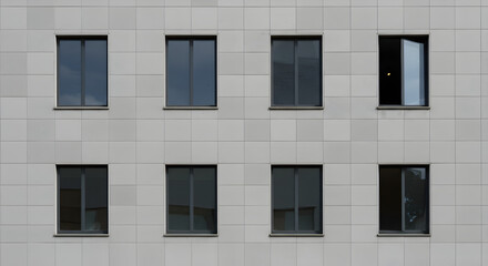 Gray Concrete Building Facade with Symmetrical Window Pattern and One Window Slightly Open on a Bright Sunny Day