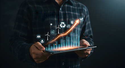 Man Holding Tablet Showing Green Energy Growth Chart with Upward Arrow in Dark Setting