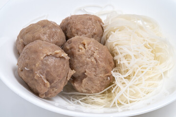 A white bowl with four beef balls and a side of vermicelli noodles. A simple dish highlighting protein and carbohydrates.