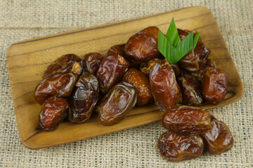 Dried date palm fruits or kurma on wooden plate for breakfasting in ramadhan. popular and healthy...