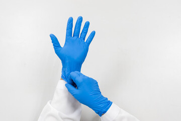 Woman doctor putting blue latex medical gloves on white background.Surgeon wearing gloves before surgery at operating room.Risk and infection control concept