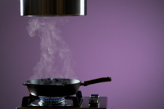 Steaming Cast Iron Frying Pan on Gas Stove with Purple Background