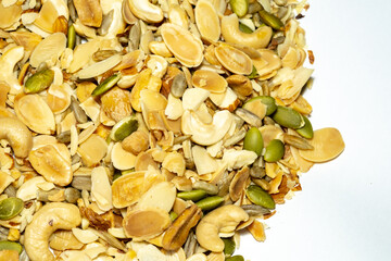 A vibrant mix of nuts and seeds, including cashews, almonds, and pumpkin seeds, is scattered across a white surface, showcasing a healthy and natural snack.