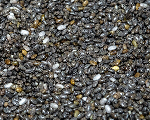 A close-up captures the intricate texture of chia seeds, a superfood packed with nutrients. Tiny black, white, and gray seeds create a rich, natural pattern.