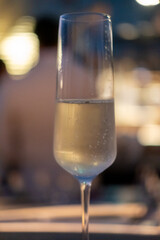 A glass of Prosecco or sparkling wine on the table with blurred bottle display on the background