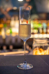 A glass of Prosecco or sparkling wine on the table with blurred bottle display on the background