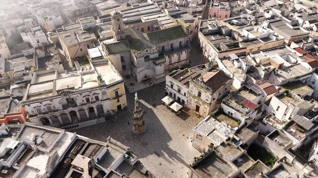 Drone shot capturing the central part of Nardo, Italy, on a misty morning. The scene features historic architecture, including a prominent church, surrounded by old buildings