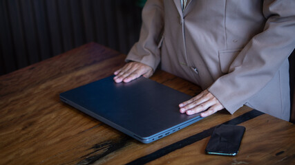 Businesswoman putting her hand on her laptop to turn it off after finishing her office work on her desk, quitting after closing a business deal