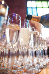 Champagne is being poured into a row of wine glasses