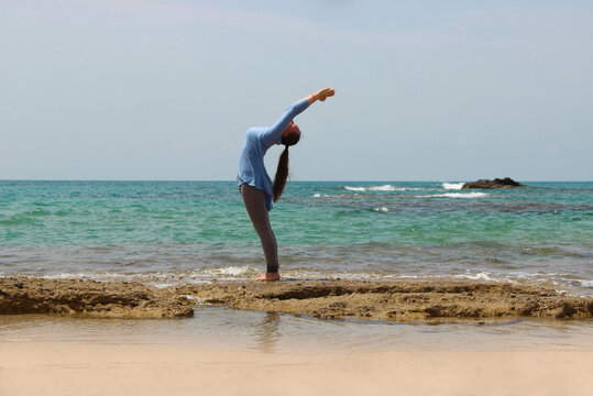 young woman doing yoga exercise on the beach