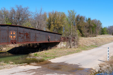 Rusty, old rail bridge used to span a creek in oil field area in West Texas. Now only used when needed by motor vehicles and pedestians.