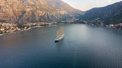 Aerial view of the Star Clipper sailing ship in the Bay of Kotor in the Adriatic Sea. The ship is set against the backdrop of the tourist town of Kotor, Montenegro.