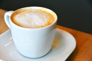 Cup of hot coffee capuchino with foam close up view