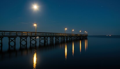 Pier at night with moonlight and reflections on water demonstrating calm and tranquility.