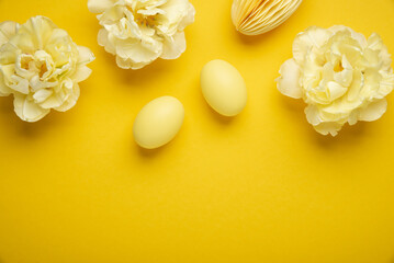 Happy Easter holiday background. Easter eggs and tulip flowers on yellow background top view.