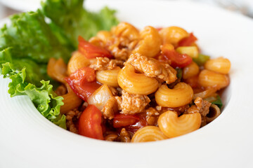 Stir fried macaroni with tomato sauce and minced pork on a white plate