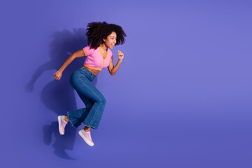 Young woman in stylish casual outfit joyfully jumping with dynamic energy against a vibrant purple background