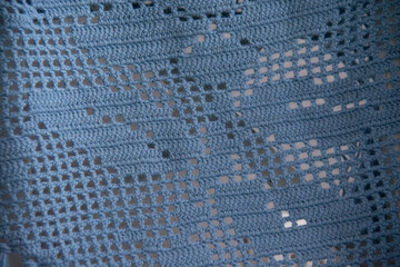 A beautiful pattern knitted from blue wool yarn using the fillet knitting technique