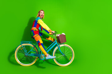 Vibrant young woman in colorful attire riding a stylish bicycle against a bright green background, radiating happiness and energy.