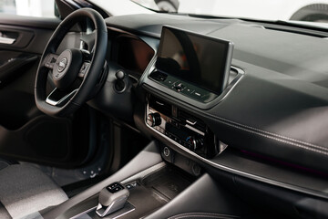Fototapeta premium Close-up of a car steering wheel in a modern new car. The interior of a stylish new car. Concept of stylish design, shopping, and car parts.