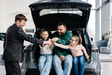 A happy young family gets the keys to their new car at a modern car dealership. The end of a test...