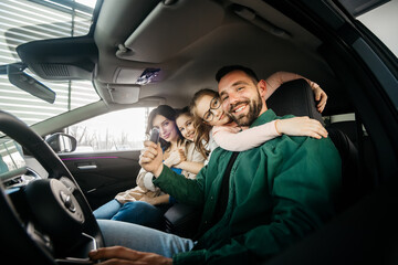 A happy young family gets the keys to their new car at a modern car dealership. The end of a test...