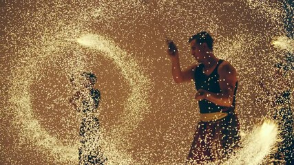 Dynamic fire show performance featuring acrobatic movements at night, slow motion isolated cinematic shot