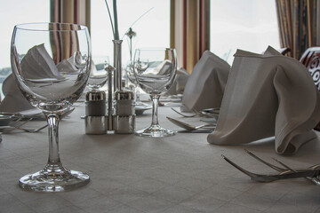 Formal and elegant ocean view dining room restaurant onboard luxury cruiseship or cruise ship liner with set tables in Belle Époque Art Nouveau interior design style and ceiling ambient lighting