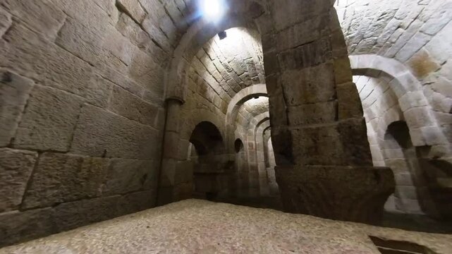 Horizontal video using a wide-angle lens to pan from left to right starting at the central apse of the crypt in Leyre Monastery, Spain. The footage captures the depth and Romanesque architecture