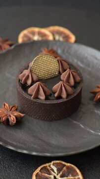 Chocolate tart or dessert with fruit and nuts. Sweet pastries on a dark concrete background