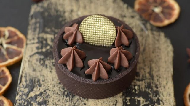 Chocolate tart or dessert with fruit and nuts. Sweet pastries on a dark concrete background
