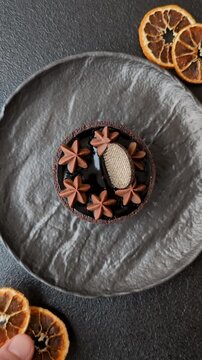 Chocolate tart or dessert with fruit and nuts. Sweet pastries on a dark concrete background