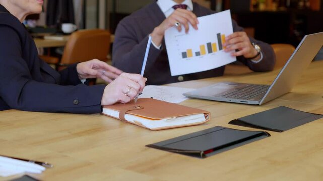 Business partners discussing financial charts during a meeting, captured in a slow-motion sequence emphasizing their collaboration and analysis