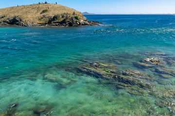 Praia do Forte, with many rocks and crystal clear waters all along the beach, mountains in the background. Cabo Frio, Rio de Janeiro.