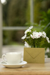 A cup of coffee, flowers and an envelope. Office desk with a cup of coffee