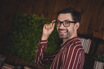Confident young man in glasses smiling in a cozy home office environment, embracing a casual yet professional appearance.