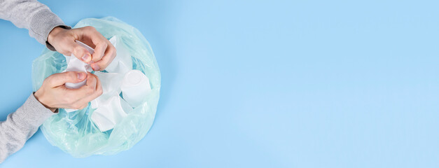 A man crumples a plastic glass on a blue background.