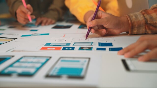 Designers create prototype sketches for a mobile app interface using pens on paper. The collaborative environment stimulates creativity and innovation in the design process. SACTR