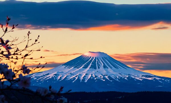 A vibrant sunset illuminates a snow-capped mountain, framed