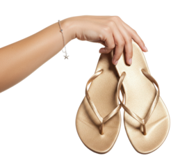 Hand holding a pair of golden flip flops in a bright setting while preparing for a sunny day outdoors on a transparent background