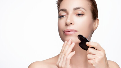 Woman using gua sha for facial skin care treatment