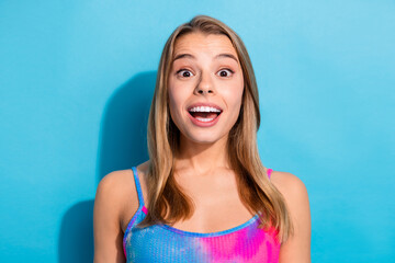 Cheerful young woman surprises with an enthusiastic expression against a vibrant blue background...