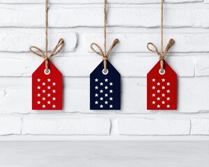 Fototapeta premium Colorful tags with star patterns hang against a bright wall, symbolizing patriotism.