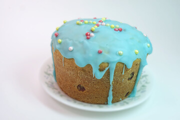 sweet Easter bread with raisin, muffin look, home baked. topping of colorful small sugar nonpareils, arranged on cyan melted sugar glaze